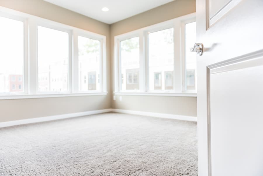 Empty bedroom entrance in new modern luxury apartment home with many large windows, bright light and carpet